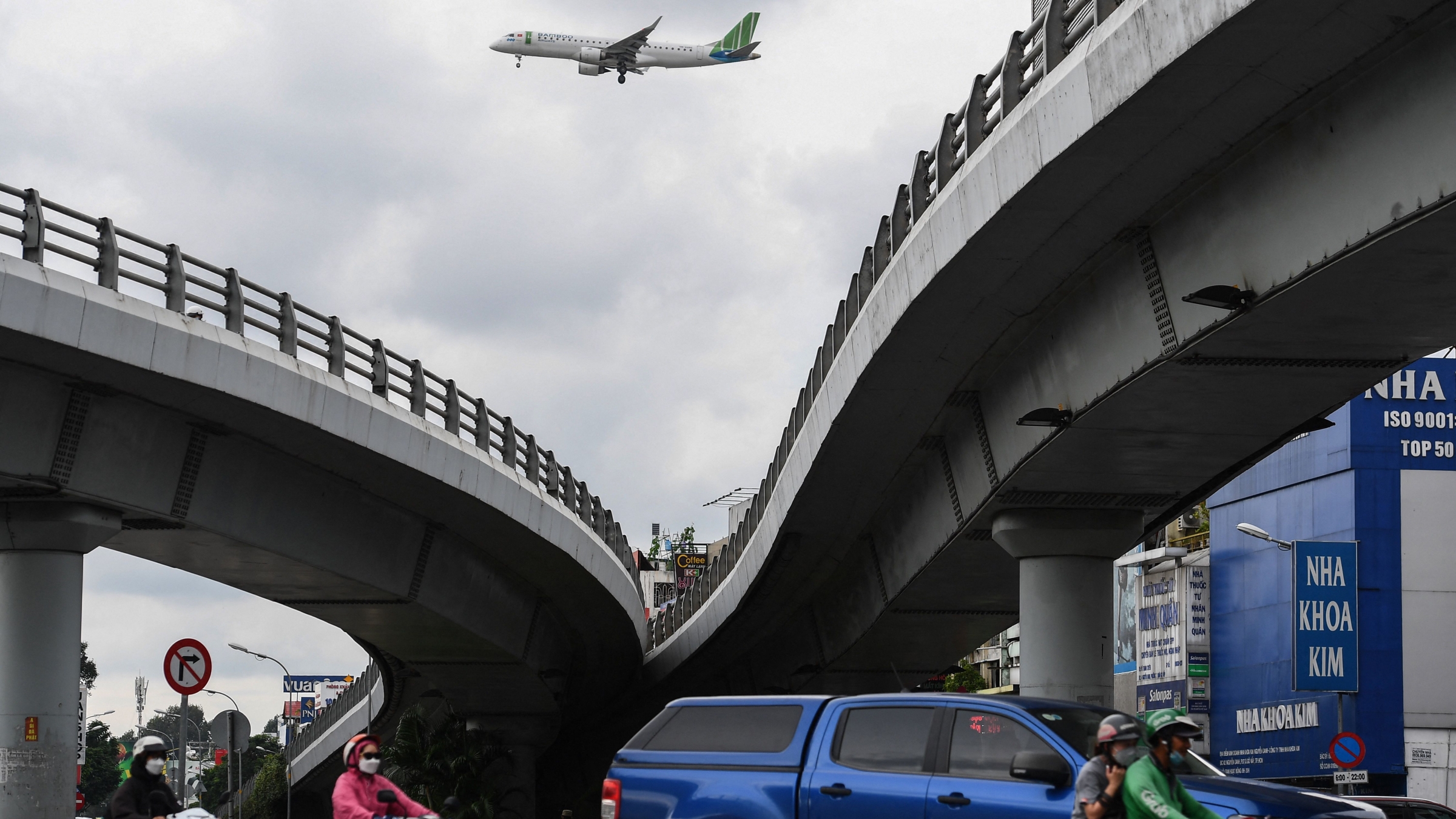 An airplane flies over commuters on a street in Ho Chi Minh City on September 22, 2022. Tan Son Nhat International Airport has been operating well over capacity for years, but efforts to build a third terminal have been slowed due, in part, to what analysts say are unintended consequences of an anti-corruption crackdown.聽